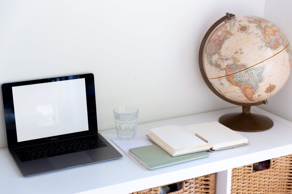 mesa com notebook, livro aberto e globo terrestre