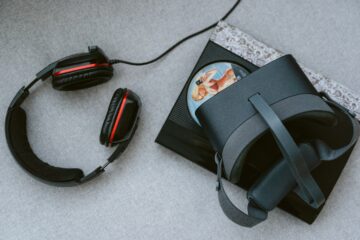 um fone, um video game e um oculos de jogos em cima de uma superficie branca